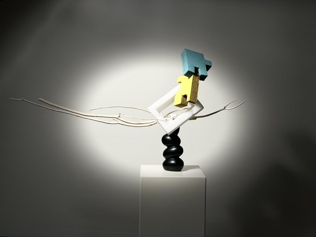 A sculptural arrangement of dried branches and pale packing material, balanced like a drawing in the air.